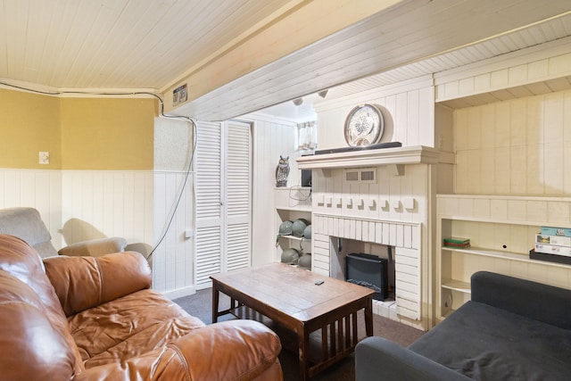 living room with carpet, visible vents, a wainscoted wall, wood ceiling, and a brick fireplace