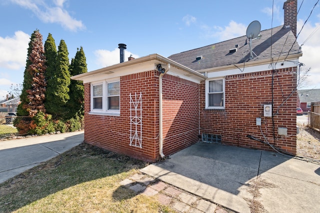 view of side of property with fence, brick siding, and a chimney