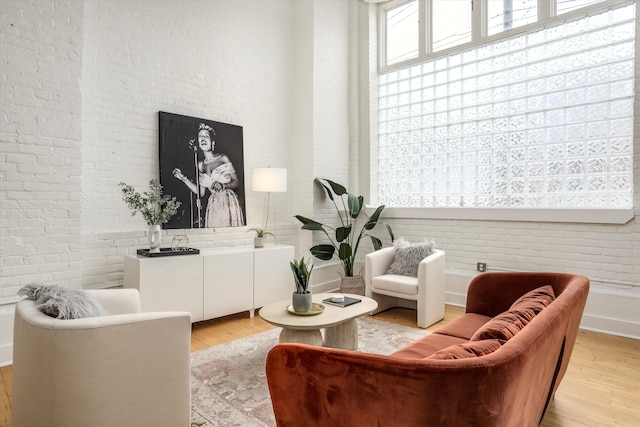 living area with light wood-type flooring and brick wall