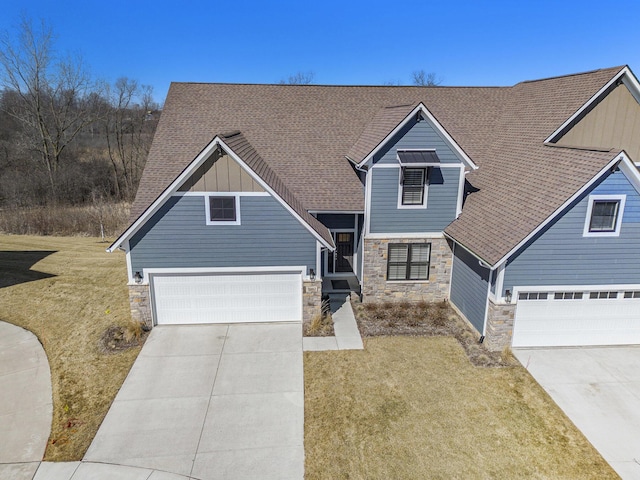 view of front of house featuring stone siding, board and batten siding, concrete driveway, and a front yard