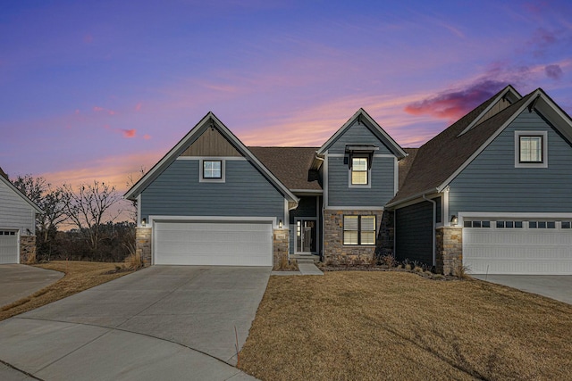 view of front facade featuring stone siding, an attached garage, concrete driveway, and a yard