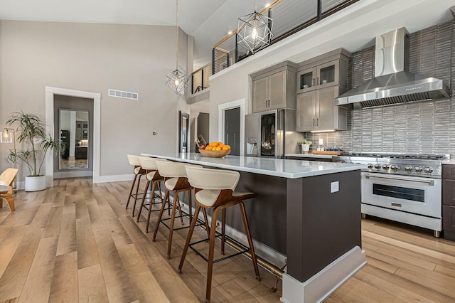 kitchen with visible vents, a center island, light wood-type flooring, appliances with stainless steel finishes, and wall chimney exhaust hood