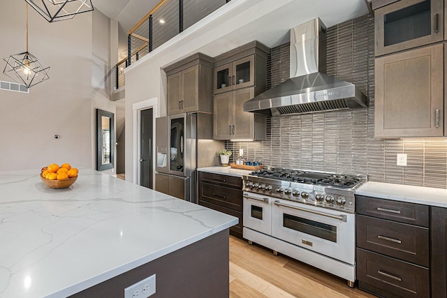 kitchen with light wood finished floors, appliances with stainless steel finishes, tasteful backsplash, and wall chimney exhaust hood