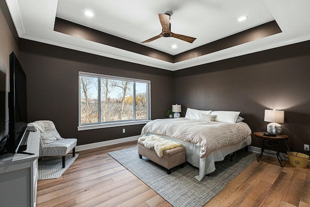 bedroom featuring baseboards, recessed lighting, ceiling fan, light wood-style floors, and a raised ceiling