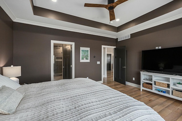 bedroom featuring wood finished floors, visible vents, baseboards, recessed lighting, and a raised ceiling