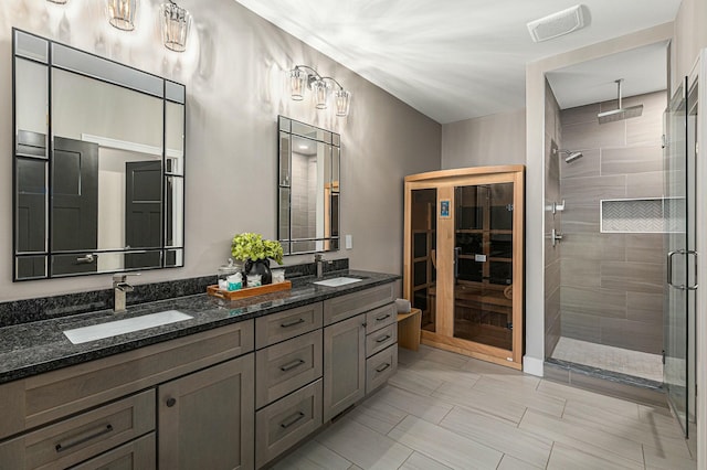 full bathroom with double vanity, visible vents, a stall shower, and a sink