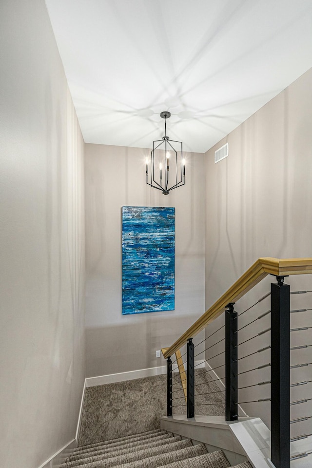 stairway with baseboards, visible vents, carpet floors, and an inviting chandelier