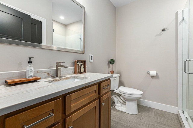 bathroom with vanity, baseboards, a stall shower, tile patterned floors, and toilet