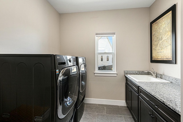 washroom featuring a sink, baseboards, cabinet space, and separate washer and dryer