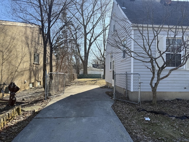 view of side of home with roof with shingles and fence