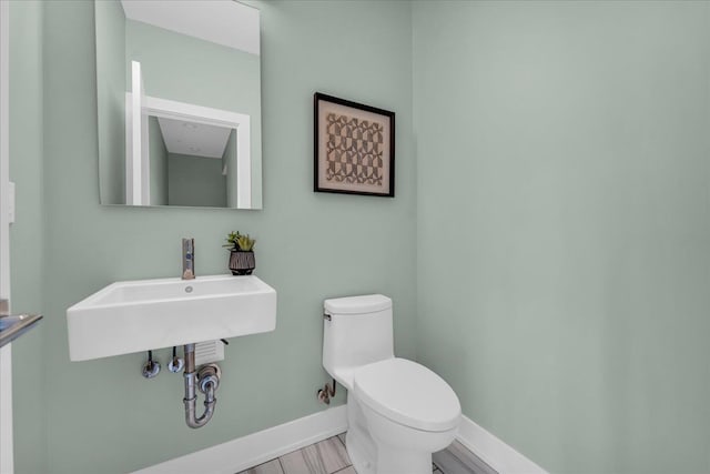 bathroom with a sink, baseboards, and toilet