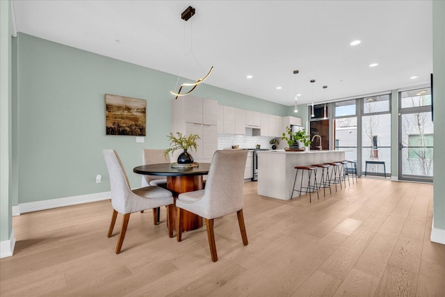 dining space featuring light wood-style flooring, recessed lighting, baseboards, and expansive windows