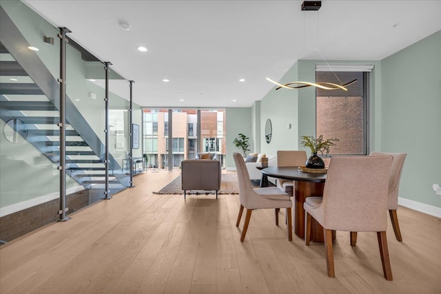 dining room featuring baseboards, stairway, expansive windows, recessed lighting, and light wood-style flooring