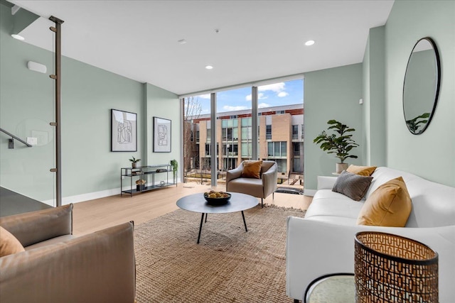 living area with a wall of windows, baseboards, wood finished floors, and recessed lighting