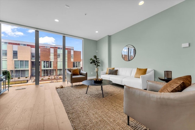 living area featuring a wall of windows, baseboards, hardwood / wood-style floors, and recessed lighting