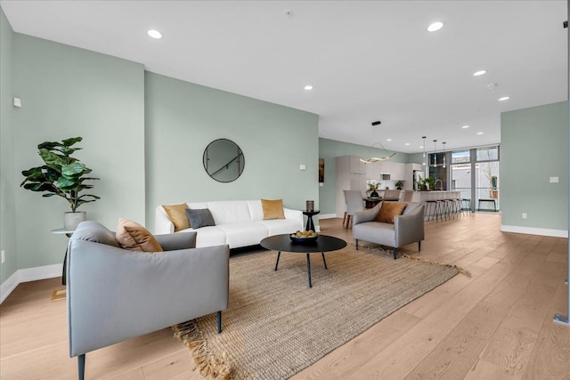 living room with recessed lighting, baseboards, and light wood finished floors