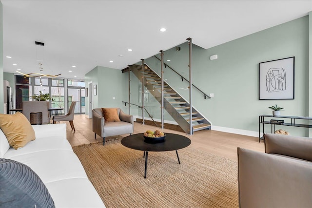 living room featuring light wood finished floors, baseboards, stairway, expansive windows, and recessed lighting