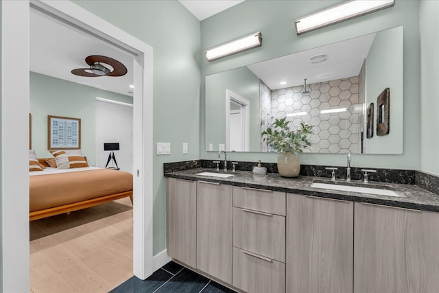 full bath featuring ensuite bath, double vanity, a tile shower, and a sink