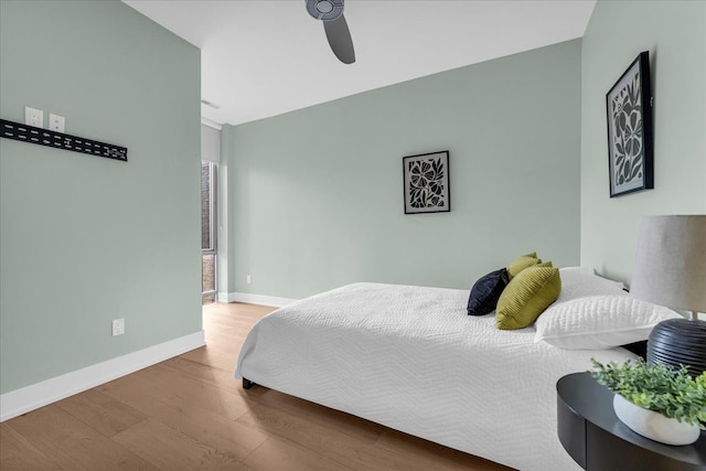 bedroom with a ceiling fan, baseboards, and wood finished floors