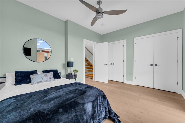 bedroom with baseboards, a ceiling fan, multiple closets, and wood finished floors