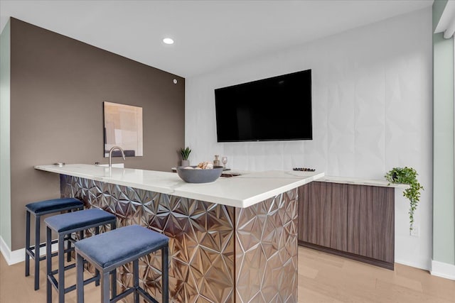 bar featuring recessed lighting, light wood-type flooring, baseboards, and a sink