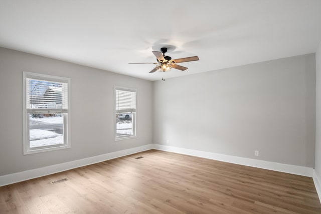 spare room with baseboards, ceiling fan, a healthy amount of sunlight, and light wood-style floors