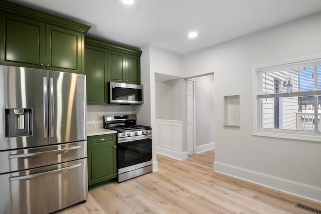 kitchen featuring green cabinetry, appliances with stainless steel finishes, baseboards, visible vents, and light wood-style floors