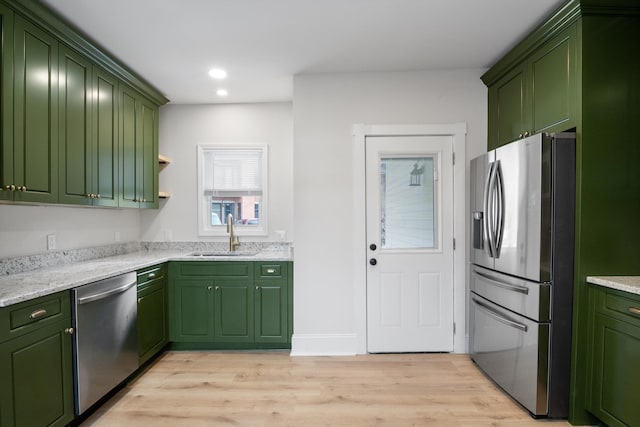 kitchen featuring stainless steel appliances, recessed lighting, a sink, green cabinetry, and light wood-type flooring