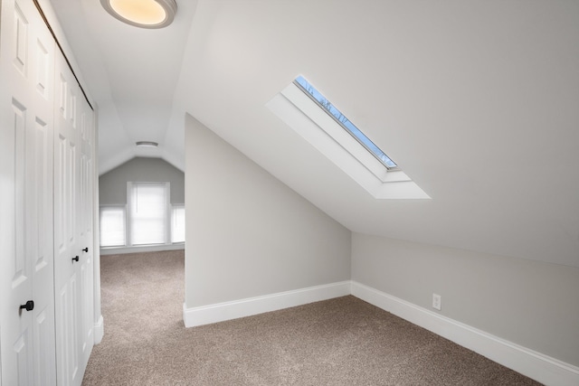 additional living space with baseboards, lofted ceiling with skylight, and carpet flooring