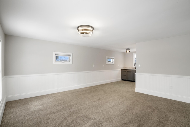 unfurnished room featuring a wainscoted wall and light carpet