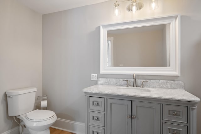 bathroom featuring baseboards, toilet, vanity, and wood finished floors