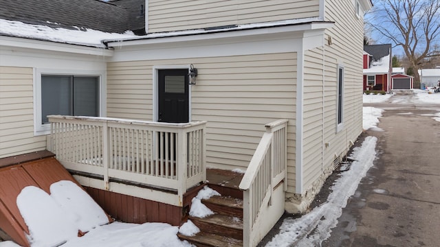 snow covered property entrance with a wooden deck