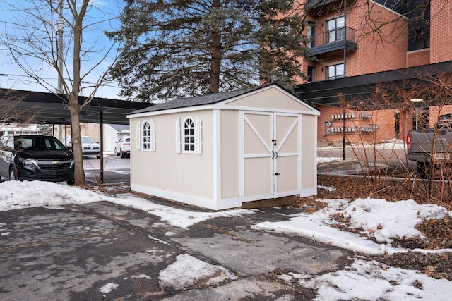 snow covered structure featuring a shed and an outdoor structure