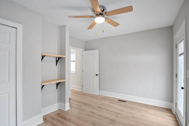 interior space featuring baseboards, ceiling fan, visible vents, and light wood finished floors