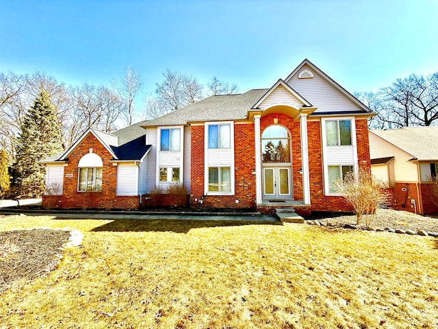 view of front of home with brick siding, french doors, and a front lawn