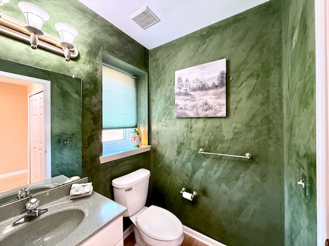 half bath with visible vents, toilet, and vanity