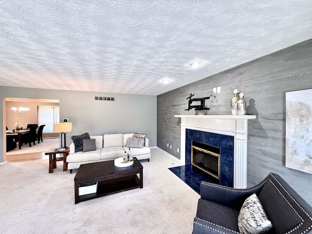 carpeted living room featuring visible vents, a premium fireplace, lofted ceiling, a textured ceiling, and a chandelier