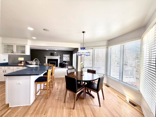 dining room featuring visible vents, a fireplace, and light wood finished floors