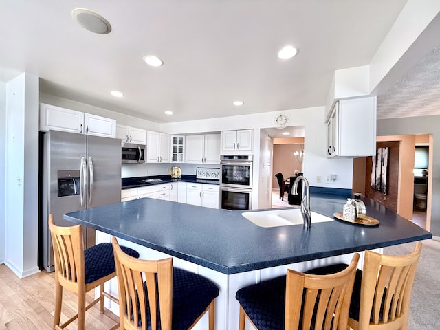 kitchen featuring a sink, dark countertops, stainless steel appliances, a peninsula, and glass insert cabinets