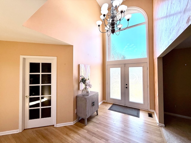 entryway with visible vents, wood finished floors, french doors, a high ceiling, and an inviting chandelier