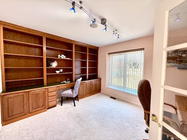 home office featuring baseboards, visible vents, built in study area, rail lighting, and light colored carpet