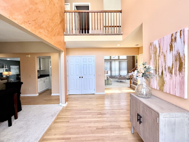 entryway featuring baseboards, a high ceiling, and light wood-style floors