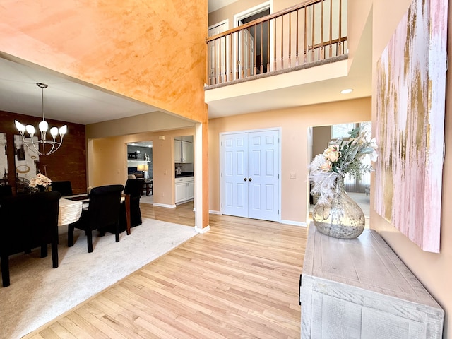 foyer with an inviting chandelier, baseboards, light wood-type flooring, and a towering ceiling