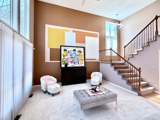 living area with ceiling fan with notable chandelier, baseboards, stairs, and carpet