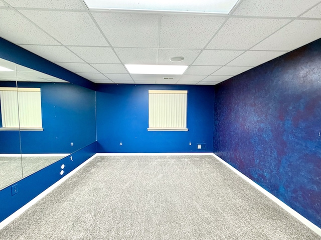 below grade area with carpet flooring, a paneled ceiling, and baseboards