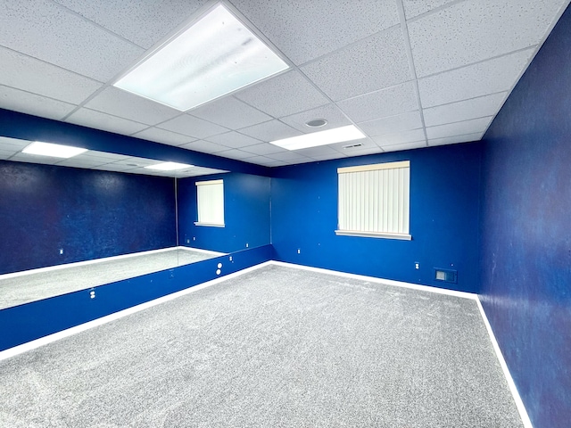 below grade area with carpet, baseboards, and a drop ceiling