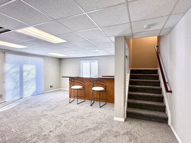 interior space featuring a bar, stairway, carpet flooring, and baseboards