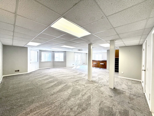 below grade area with visible vents, a drop ceiling, stairway, carpet floors, and baseboards