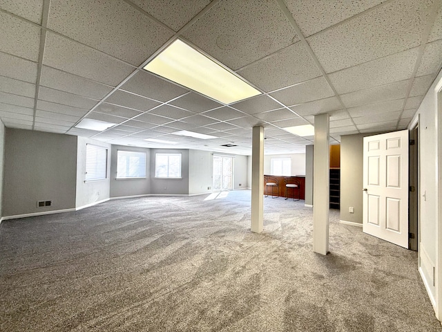 basement with a paneled ceiling, visible vents, baseboards, and carpet