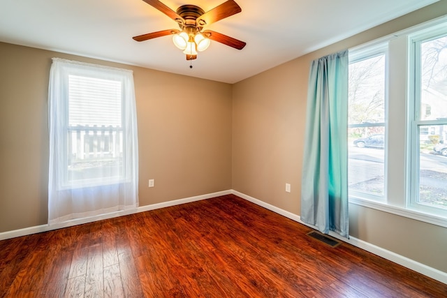 unfurnished room with dark wood-style floors, visible vents, a healthy amount of sunlight, and baseboards